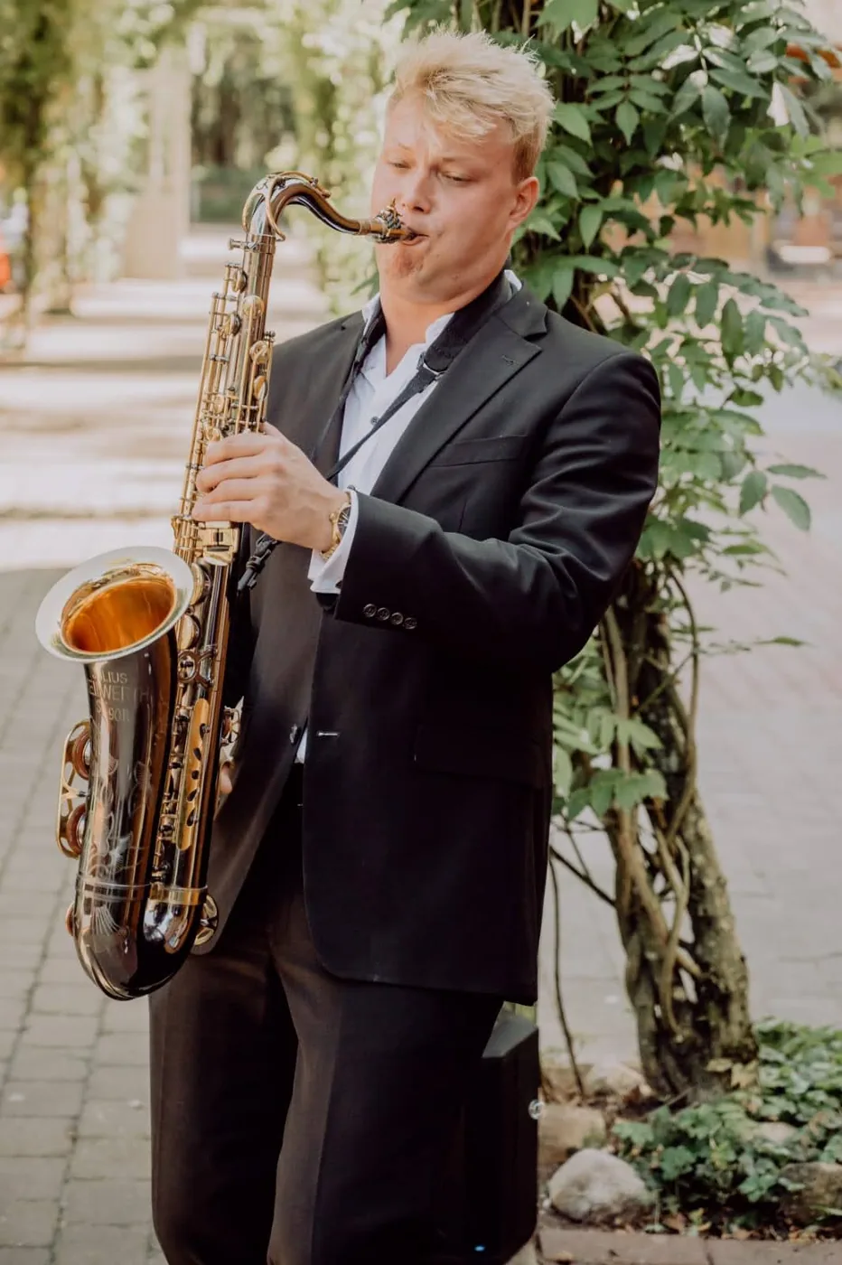Felix Tönnies mit Tenorsaxophon an einer begrünten Pergola